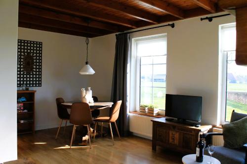 a living room with a table and chairs and a television at B&B de Friese Meren, helemaal privé voor jou! in Tjerkgaast