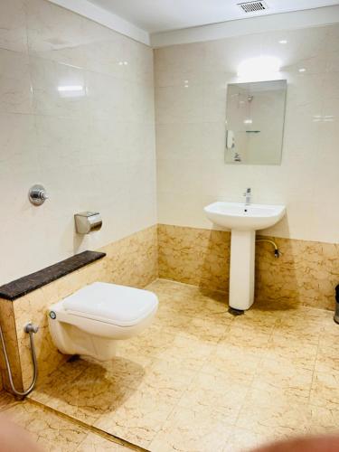 a bathroom with a toilet and a sink at Hotel Grand Bee , Yeshwanthpur Junction in Bengaluru