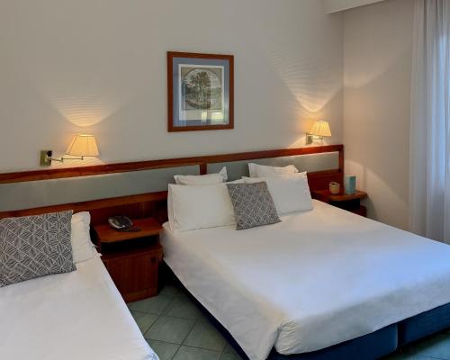 a hotel room with two beds and two lamps at Hotel Marad in Torre del Greco