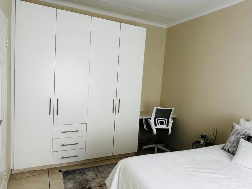a bedroom with white cabinets and a desk at Sweet Daisies Apartment in Mbabane