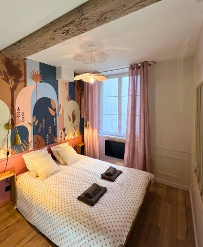 a bedroom with a bed with two towels on it at Le secret du Damier by Miss K in Mâcon