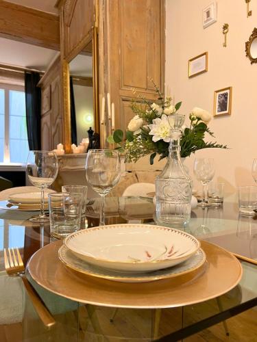 a table with plates and glasses and a vase with flowers at Le secret du Damier by Miss K in Mâcon