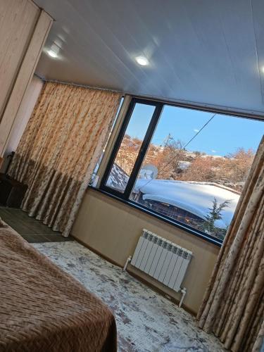 a bedroom with a large window and a bed and a radiator at Green Veranda in Nurekata