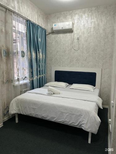 a bedroom with a white bed with a blue headboard at Айымхан in Almaty