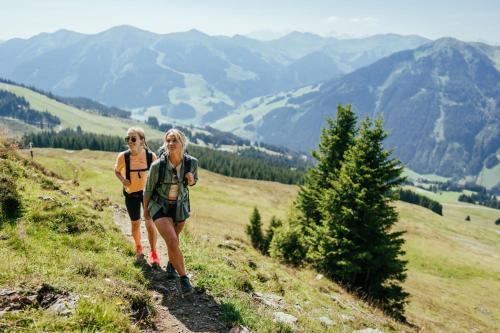 two women walking down a hill on a mountain at Der Unterschwarzachhof in Saalbach Hinterglemm