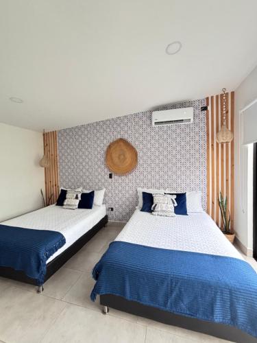 a bedroom with two beds with blue and white sheets at Casa Río Quindío in La Tebaida