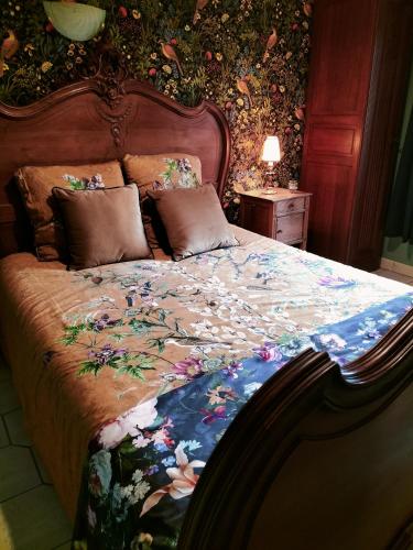 Ce lit se trouve dans une chambre dotée d'un papier peint fleuri. dans l'établissement les hortensias La Souris Des Champs, à Étival-Clairefontaine