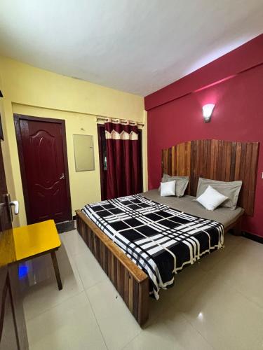 a bedroom with a large bed with a red wall at Kodaikanal NPM Residency Hotel in Kodaikānāl