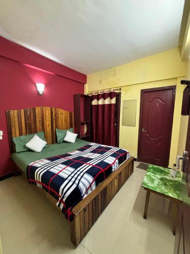 a bedroom with a bed and a red wall at Kodaikanal NPM Residency Hotel in Kodaikānāl