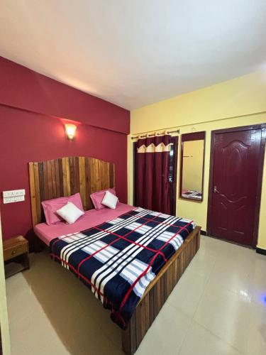 a bedroom with a large bed with red walls at Kodaikanal NPM Residency Hotel in Kodaikānāl