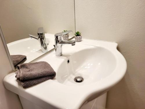 un lavabo blanc dans une salle de bain avec un miroir dans l'établissement Maguilon H - 10 personnes - Proche rivière et Vals bains, à Lalevade-dʼArdèche