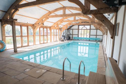an indoor swimming pool with a large room with wooden ceilings at The Shippon Barn - A delightful haven for families in Wirral