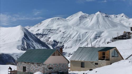 una casa en la nieve con una montaña en el fondo en Gudauri Private Cottage 2, en Gudauri