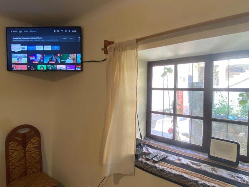 a living room with a window and a flat screen tv at Casa Cusco Centro in Cusco