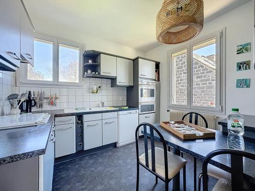 une cuisine avec des armoires blanches et une table avec des chaises dans l'établissement Chez Maurice Maison familiale & Campagne, à Mazaye
