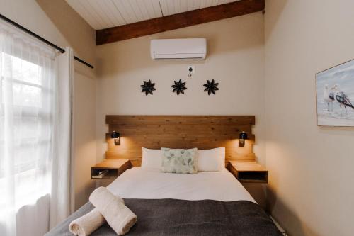 a bedroom with a bed with two night stands and a window at Afri Villa Stays - Luxury Bush Villa Hyena in Marloth Park