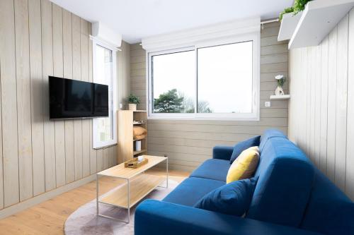 Una sala de estar con un sofá azul y un televisor. en Jade's House, en Donville-les-Bains