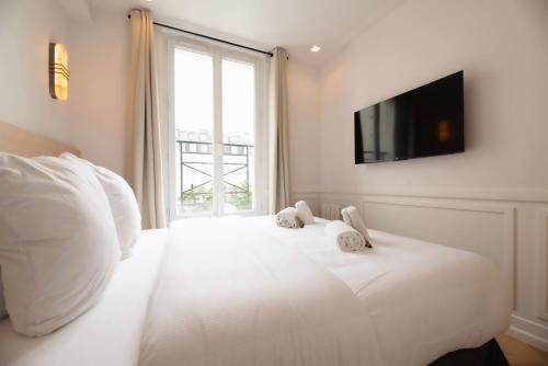 - une chambre avec un lit blanc et une télévision murale dans l'établissement Austerlitz Residence, à Paris
