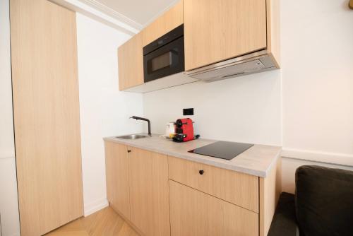 une cuisine avec un comptoir avec un évier et un micro-ondes dans l'établissement Austerlitz Residence, à Paris