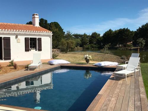 une piscine avec deux chaises et une maison dans l'établissement Villa pour 10 avec piscine et jardin, à Noirmoutier-en-l'lle