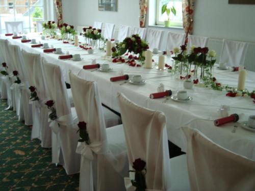 a long row of tables with white chairs and flowers at Hotel Zum Bären in Kurort Altenberg