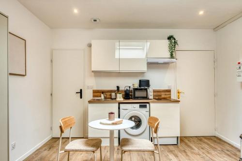 une cuisine avec un lave-linge, une table et des chaises dans l'établissement La Suite Sable - Cosy studio - Proche Métro B, à Oullins