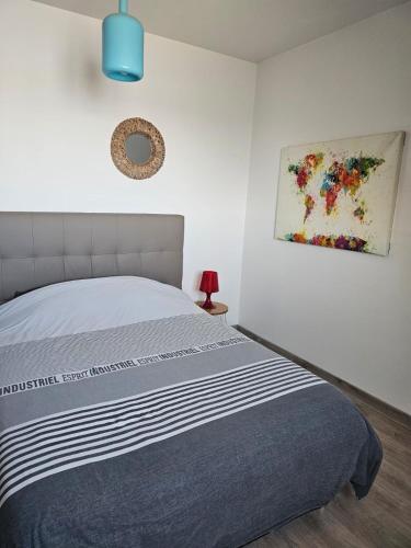 une chambre avec un lit et un tableau au mur dans l'établissement Très bel appartement vues mer, à Larmor-Plage