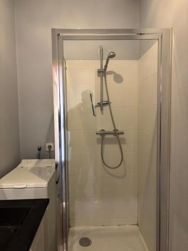 une douche avec une porte vitrée à côté d'un lavabo dans l'établissement Très bel appartement vues mer, à Larmor-Plage