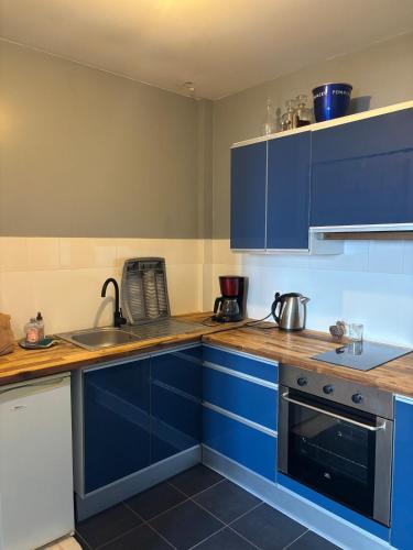 une cuisine avec des armoires bleues et un évier dans l'établissement Très bel appartement vues mer, à Larmor-Plage