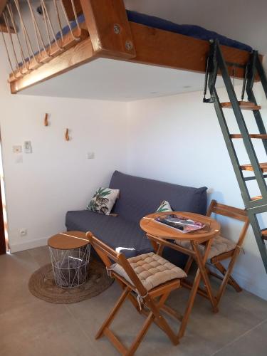 Cette chambre dispose d'un canapé, d'une table et d'une échelle. dans l'établissement Studio Valcros, La Londe, à La Londe-les-Maures