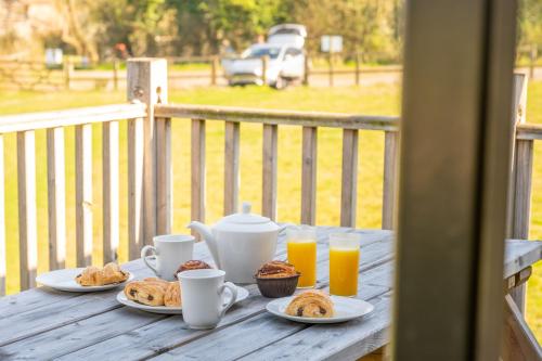 a table with plates of food and cups of orange juice at Skylark - Sweffling Hall in Rendham