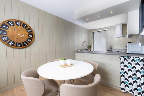 eine Küche mit einem Tisch und einer Uhr an der Wand in der Unterkunft Jade's House in Donville-les-Bains