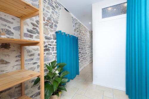 einen Flur mit blauen Vorhängen und einer Steinmauer in der Unterkunft Jade's House in Donville-les-Bains