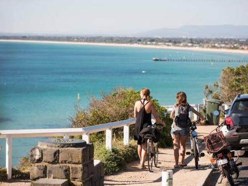 two people walking their bikes near the ocean at Bayside Bungalow in Frankston