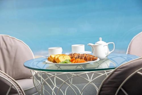 a glass table with a plate of food on it at Pearl SeaBreeze Suites in Rethymno Town
