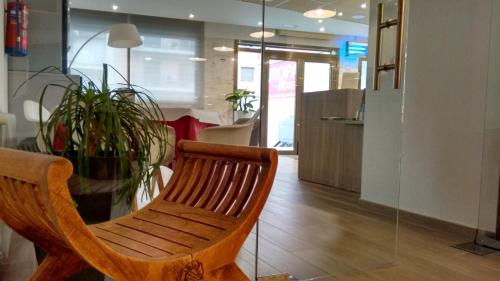 a wooden chair sitting next to a glass table at Hotel Europa in Figueres