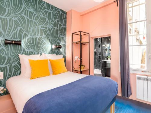 - une chambre dotée d'un lit avec des oreillers orange et bleu dans l'établissement Merveil - Luxury Suite - Marais - Saint Denis I, à Paris