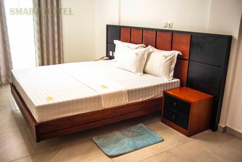 Un dormitorio con una cama grande con cabecero de madera. en Residence Hotel Smart douala, en Douala