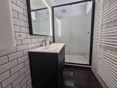 une salle de bain blanche avec un lavabo et une douche dans l'établissement Grand balcon face mer appartement 2 chambres rénové, à Saint-Jean-de-Monts