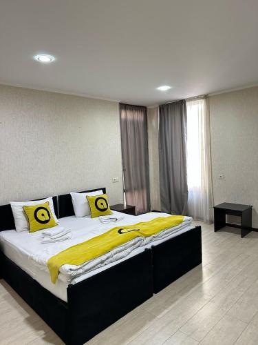 a bedroom with a large bed with yellow sheets at Aura Plaza Hotel in Tbilisi City