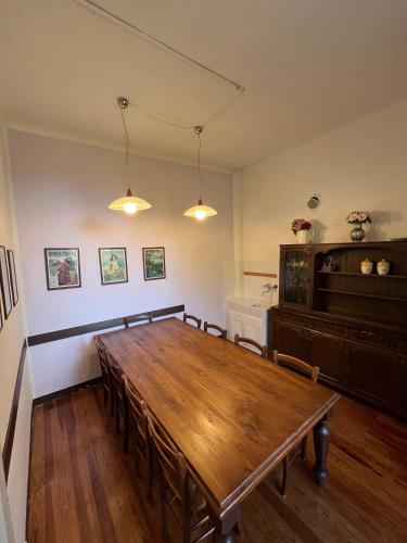 a dining room with a wooden table and a piano at B&B Villa Mirandola in Brunate