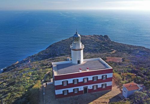 a lighthouse on a hill next to the ocean at Faro Capel Rosso in Isola del Giglio
