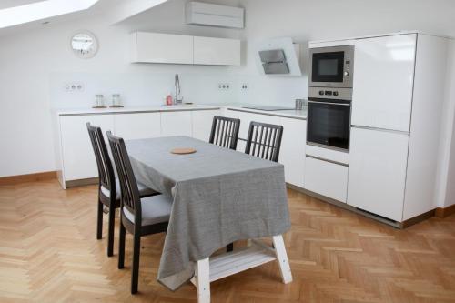 une cuisine avec des armoires blanches et une table et des chaises dans l'établissement Spacious apartment of 90 m2 in Toulouse, à Toulouse