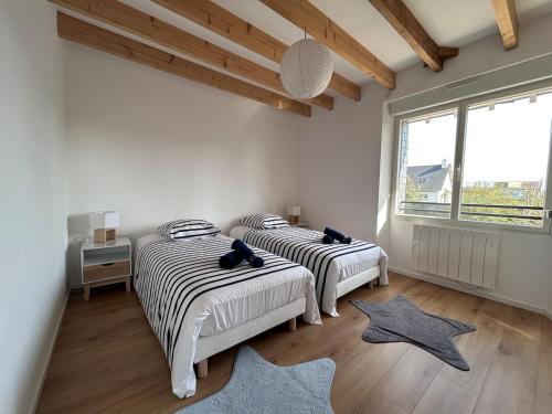 two beds in a room with two windows and a rug at La Pause Binicaise - Maison proche plage in Binic-Etables-sur-Mer