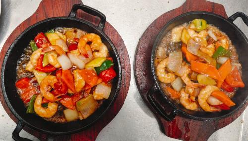 two frying pans filled with shrimp and vegetables on a table at HOSTAL DON JAVIER in Ororbia