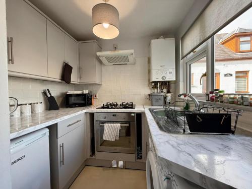 a kitchen with a sink and a stove top oven at Sea Breeze Cottage short walk to the beach, Nairn in Nairn