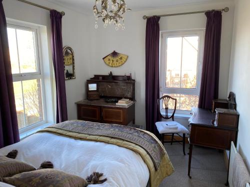 a bedroom with a bed and a desk and windows at Atlantic Bliss in Portstewart