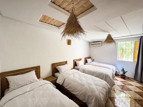 three beds in a room with white sheets at Dar Surfana Morocco in Aourir