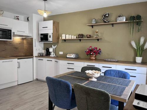 une cuisine avec une table et des chaises et une cuisine avec des armoires blanches dans l'établissement Appartement à Cauterets avec terrasse et parking - FR-1-812-20, à Cauterets