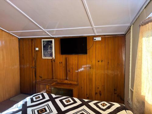 a bedroom with a bed and a tv on a wooden wall at Nani House the mall road shimla in Shimla
